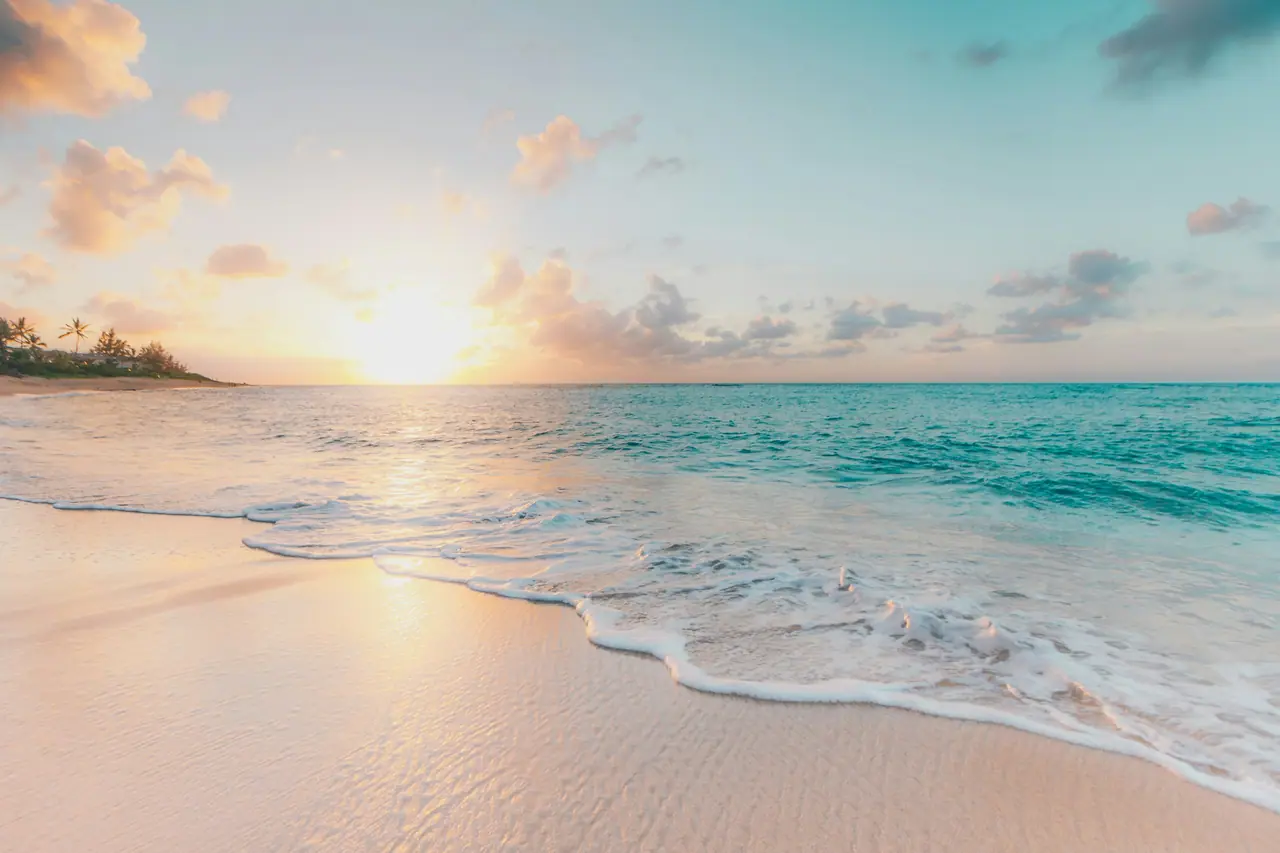 Plage au soleil couchant, vagues calmes sur le sable