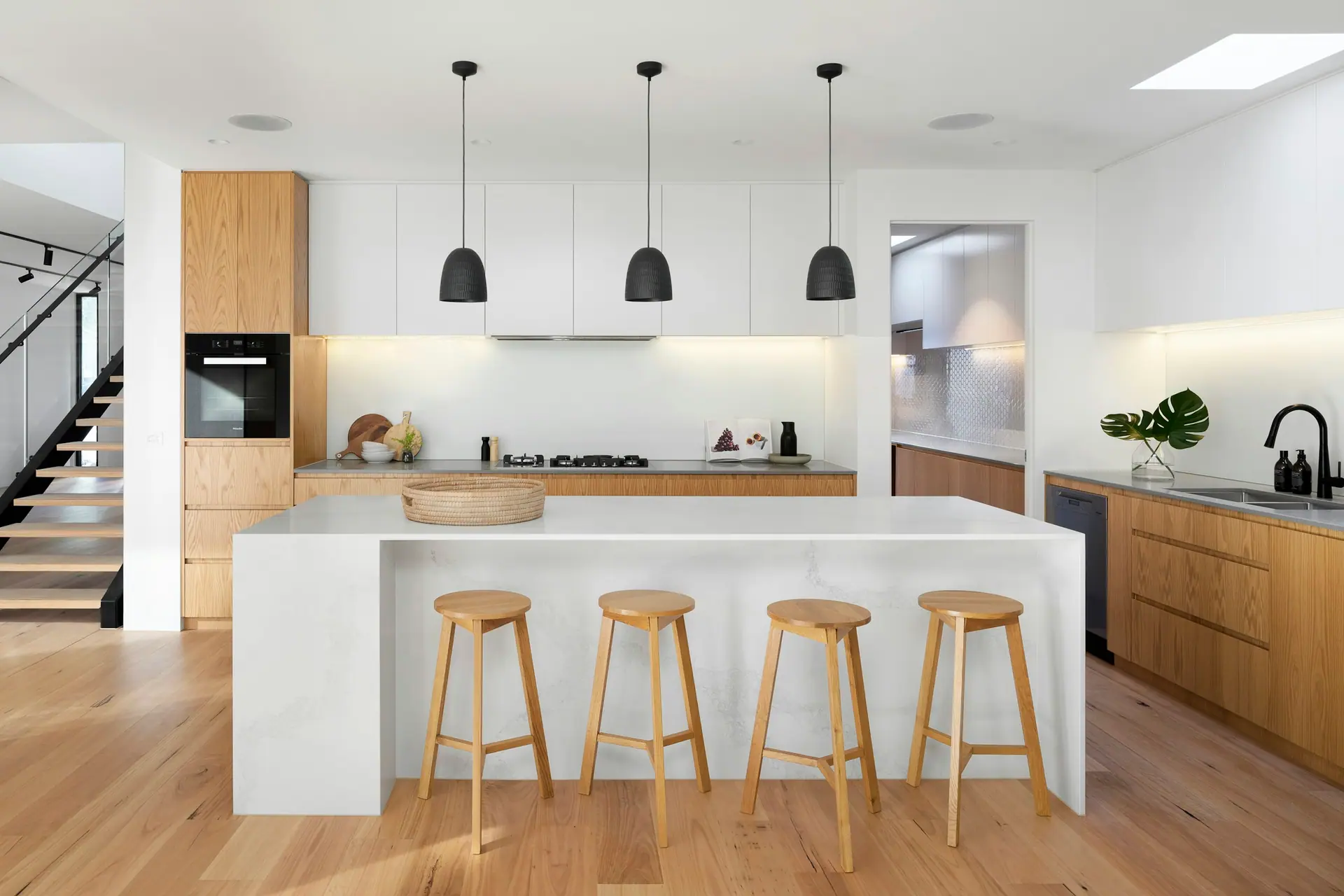 Cuisine ouverte avec îlot central et tabourets de bois clair